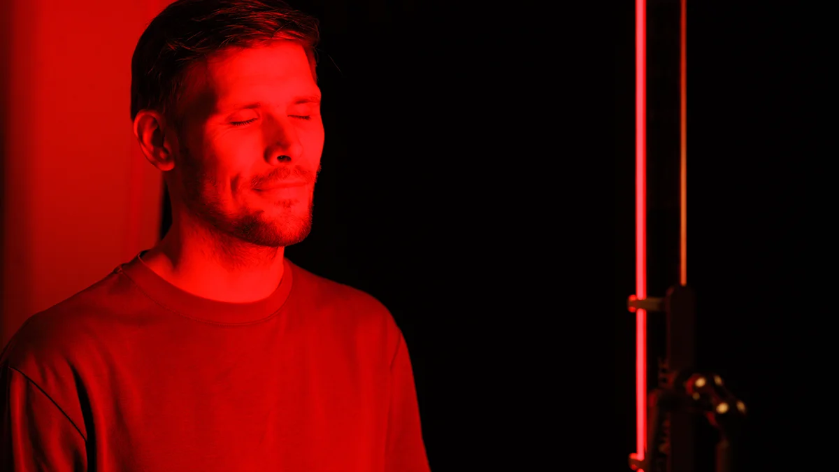 a man with closed eyes in front of a red led panel